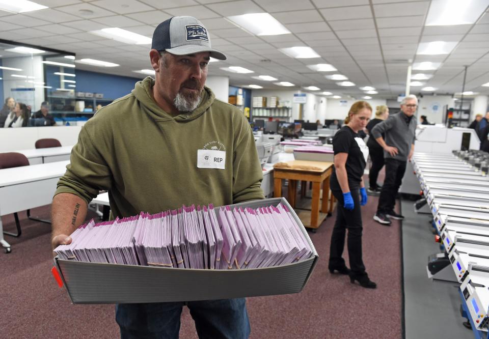 A worker carries a tote box of ballot that have been through the sorting mechine at the Washoe County Registrar’s Office on election night Nov. 8, 2022.