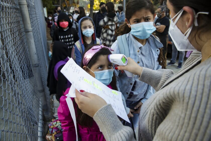 Los Angeles, CA - January 14: Yesenia Torres, right, screens students coming to Elysian Heights Elementary Arts Magnet on Friday, Jan. 14, 2022 in Los Angeles, CA. (Irfan Khan / Irfan Khan)