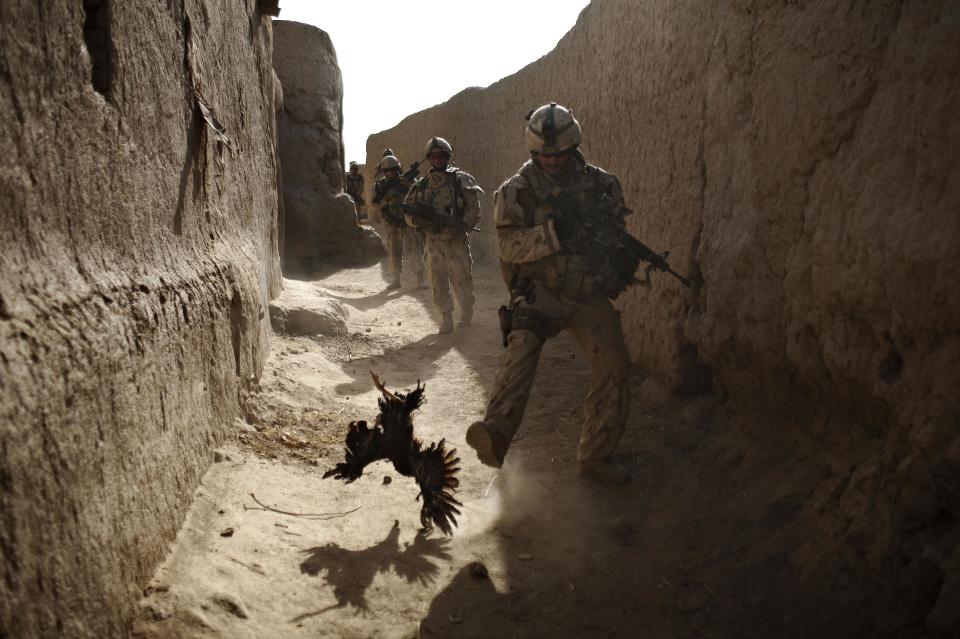 FILE - In this Saturday, Sept. 11, 2010 file photo made by Associated Press photographer Anja Niedringhaus, a Canadian soldier with the 1st RCR Battle Group, The Royal Canadian Regiment, chases a chicken seconds before he and his unit were attacked by grenades shot over the wall during a patrol in Salavat, southwest of Kandahar, Afghanistan. Niedringhaus, 48, an internationally acclaimed German photographer, was killed and an AP reporter was wounded on Friday, April 4, 2014 when an Afghan policeman opened fire while they were sitting in their car in eastern Afghanistan. (AP Photo/Anja Niedringhaus, File)