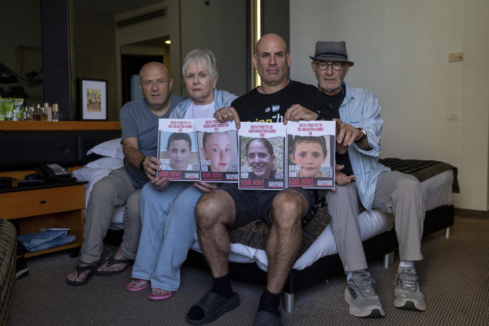 Giroa Almog, right, Varda and David Goldstein as well as Omri Almog, hold up portraits of Omri's sister, 49-year-old Chen Goldstein and her three children, 9-year-old Tal, 11-year-old Gal and 17-year-old Agam Almog-Golstein in a hotel in Tel Aviv, Israel, for evacuated Israelis, Monday, Oct. 30, 2023. The Israeli mother and her three children were abducted by Hamas militants from their home in the southern kibbutz of Kfar Aza during the militant group's unprecedented attack on Oct. 7 that resulted in the killing over 1,400 people and abduction of over 220. The assault also killed two other members of the Almog-Goldstein family, Nadav and Yam. (AP Photo/Ohad Zwigenberg)