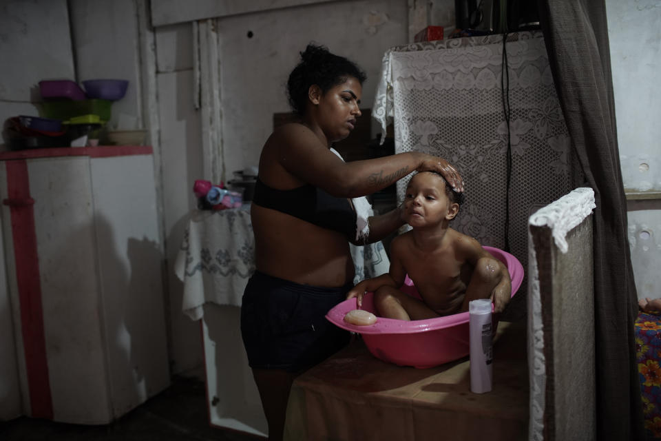 Thayane, who made a living as a manicurist before the coronavirus pandemic hit, bathes her 3-year-old daughter Melyssa in their room of an occupied building where she lives with her three daughters in Rio de Janeiro, Brazil, Thursday, March 11, 2021. During the pandemic, more than 6.5 million Brazilian women exited the workforce, dropping their participation rate below 48% — the lowest in more than a decade. (AP Photo/Silvia Izquierdo)