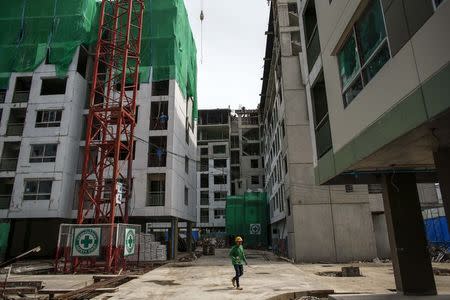 A migrant worker walks in a construction site for buildings, in Bangkok June 18, 2014. REUTERS/Athit Perawongmetha