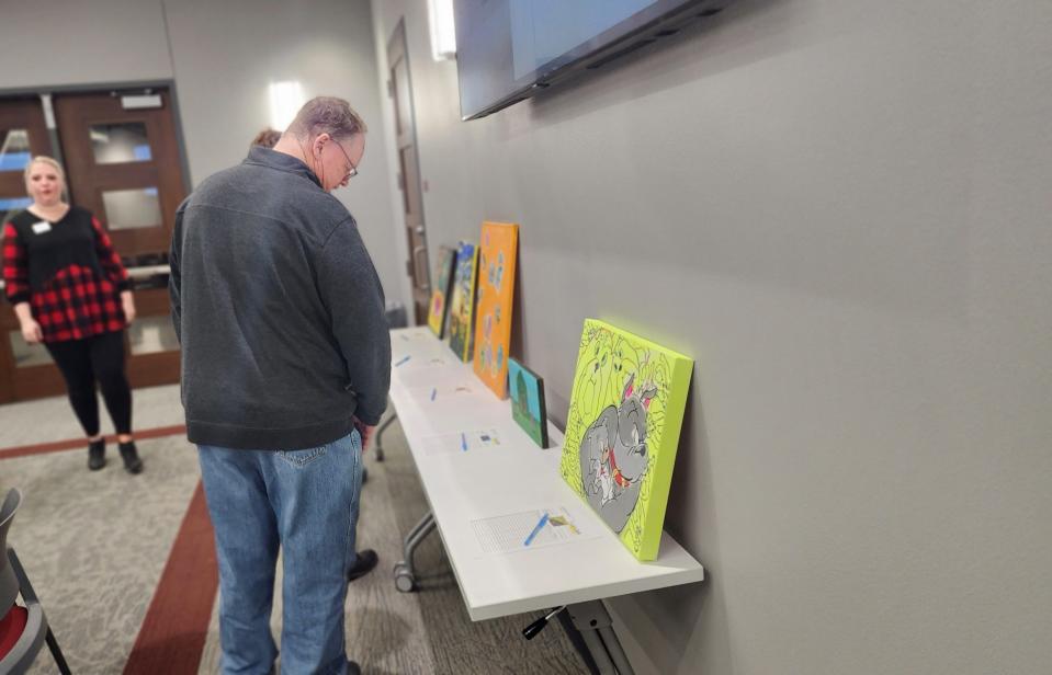 A prospective bidder looks over artwork Friday night at the HeART of CASA fundraiser in downtown Amarillo.