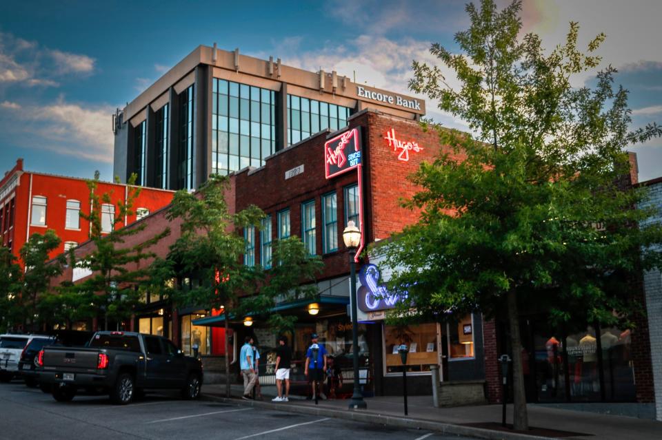 A red neon sign points to Hugo's, a basement restaurant in Fayetteville, Arkansas.