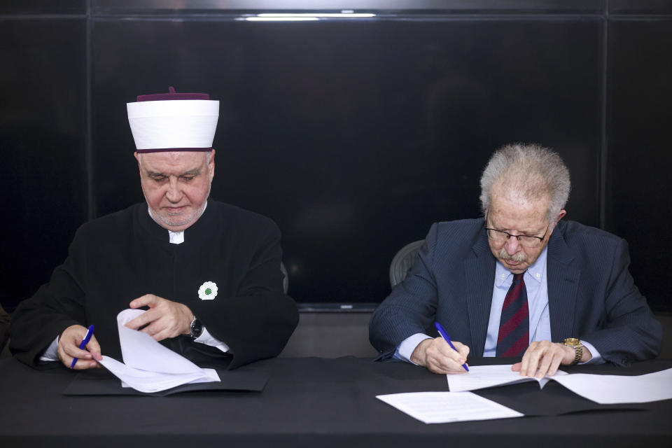 CAPTION CORRECTS ROLE OF ROSENSAFT General Counsel Emeritus of the World Jewish Congress Menachem Rosensaft, right, signs a document representing Muslim-Jewish peace initiative, with the Bosnian Grand Mufti Husein Kavazovic, at the Srebrenica Memorial Center, on International Holocaust Remembrance Day, in Potocari, Bosnia, Saturday, Jan. 27, 2024. Jews and Muslims from Bosnia and abroad gathered in Srebrenica Saturday to jointly observe International Holocaust Remembrance Day and promote compassion and dialogue amid rising global sectarian hatred fueled by Israel’s war in Gaza. (AP Photo/Armin Durgut)