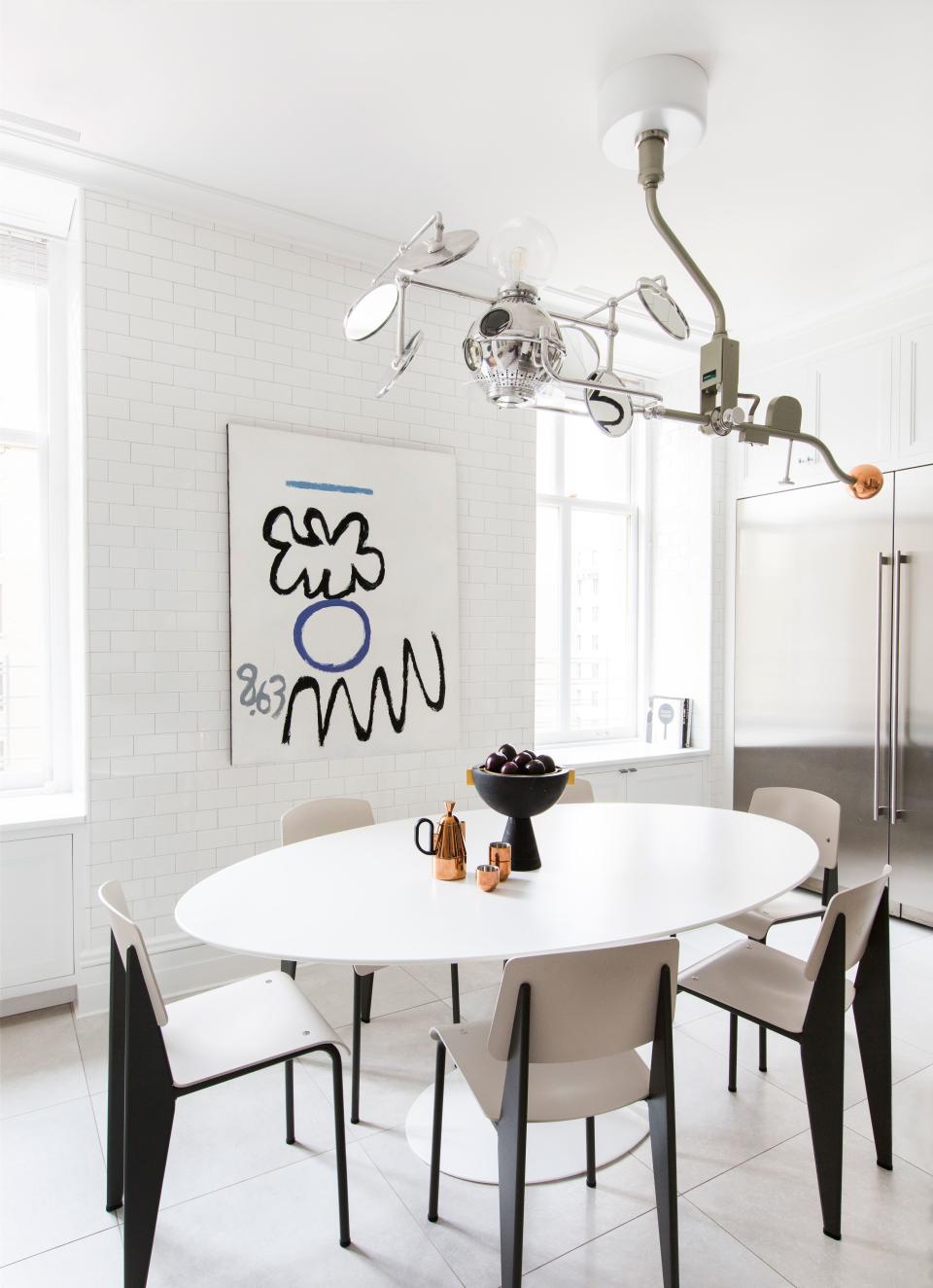 The kitchen, which was covered in white subway tiles in a nod to New York City, features a distinctive light pendant made from an old surgical light fused with Sofie Refer’s “Mega Bulb” glass fixture for andTradition. Jean Prouvé’s famous chairs surround Eero Saarinen’s equally iconic pedestal table. The abstract artwork is a painting by Raymond Hendler called The General.