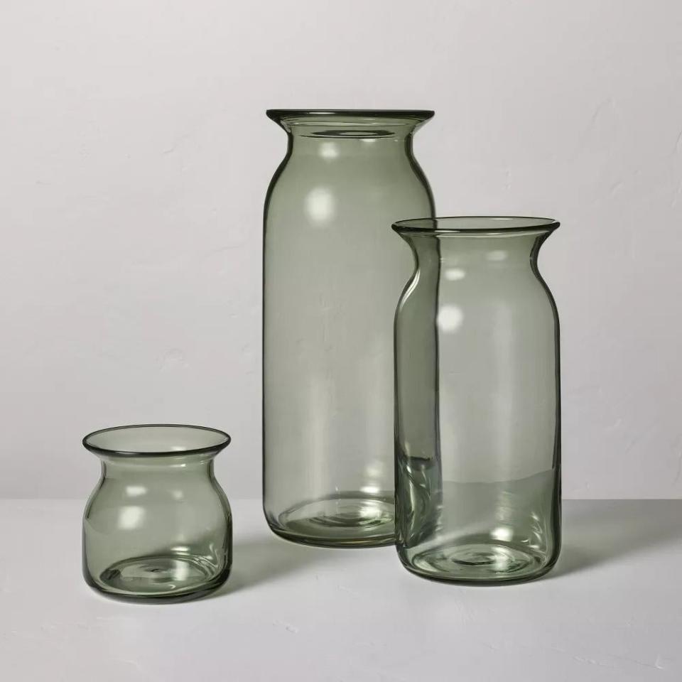 Three varying sizes of clear glass vases against a neutral background