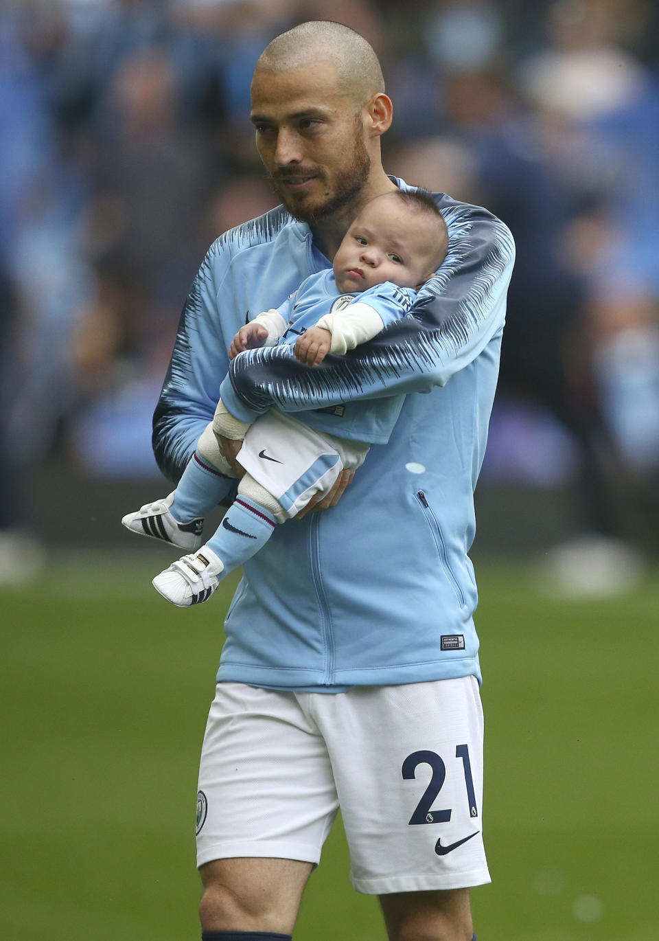 Manchester City's David Silva carries a child believed to be his son during the English Premier League soccer match between Manchester City and Huddersfield Town at the Etihad Stadium in Manchester, England, Sunday, Aug. 19, 2018. (AP Photo/Dave Thompson)