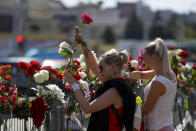 People lay flowers at the place where a protester died amid the clashes, in Minsk, Belarus, Tuesday, Aug. 11, 2020. Thousands of opposition supporters who also protested the results met with a tough police crackdown in Minsk and several other Belarusian cities for two straight nights. Belarus' health officials said over 200 people have been hospitalized with injuries following the protests, and some underwent surgery. (AP Photo/Sergei Grits)
