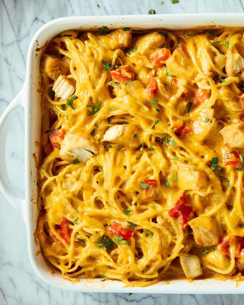 chicken, spaghetti, and red peppers covered in cheese in a casserole