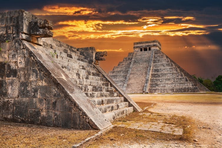 Mayan temples photographed against a stormy sky.