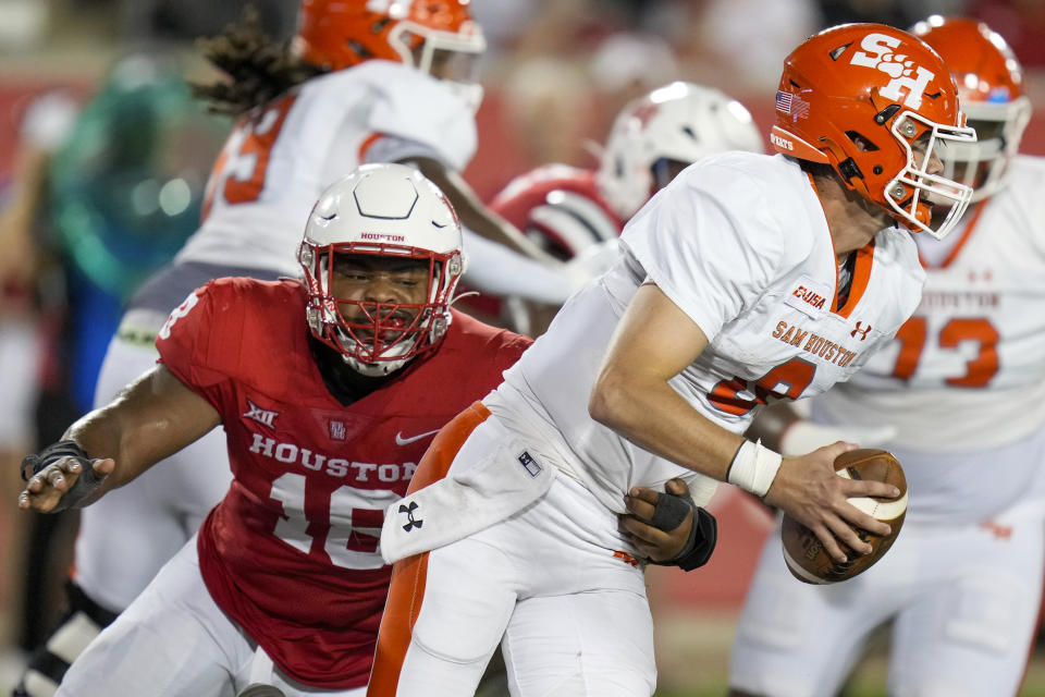 Sam Houston State quarterback Grant Gunnell, right, escapes a sack-attempt by Houston defensive lineman Anthony Holmes Jr., left, during the second half of an NCAA college football game, Saturday, Sept. 23, 2023, in Houston. (AP Photo/Eric Christian Smith)