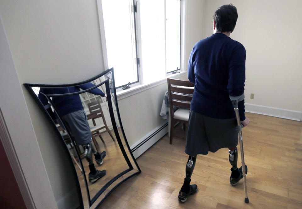 ADVANCE FOR WEEKEND USE APRIL 4-5 -- In this March 14, 2014 photo, Jeff Bauman walks past a mirror at his home in Carlisle, Mass. Bauman, who lost both his legs above the knee in the Boston Marathon bombing, played a key role in identifying the men suspected of placing the two devices. (AP Photo/Charles Krupa)