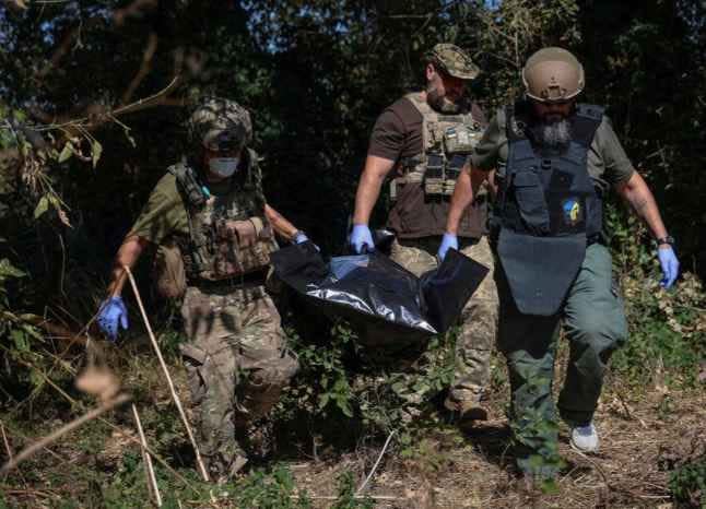 Ukrainian servicemen carry bag containing a body of a dead Russian soldier, amid Russia's attack on Ukraine, in the village of Blahodatne in Donetsk Region Ukraine September 8, 2023.