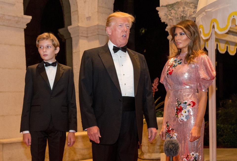 Then-President Donald Trump, first lady Melania Trump and their son Barron walk the red carpet to the ballroom for a New Year's Eva Gala at Mar-a-Lago on Dec. 31, 2017.