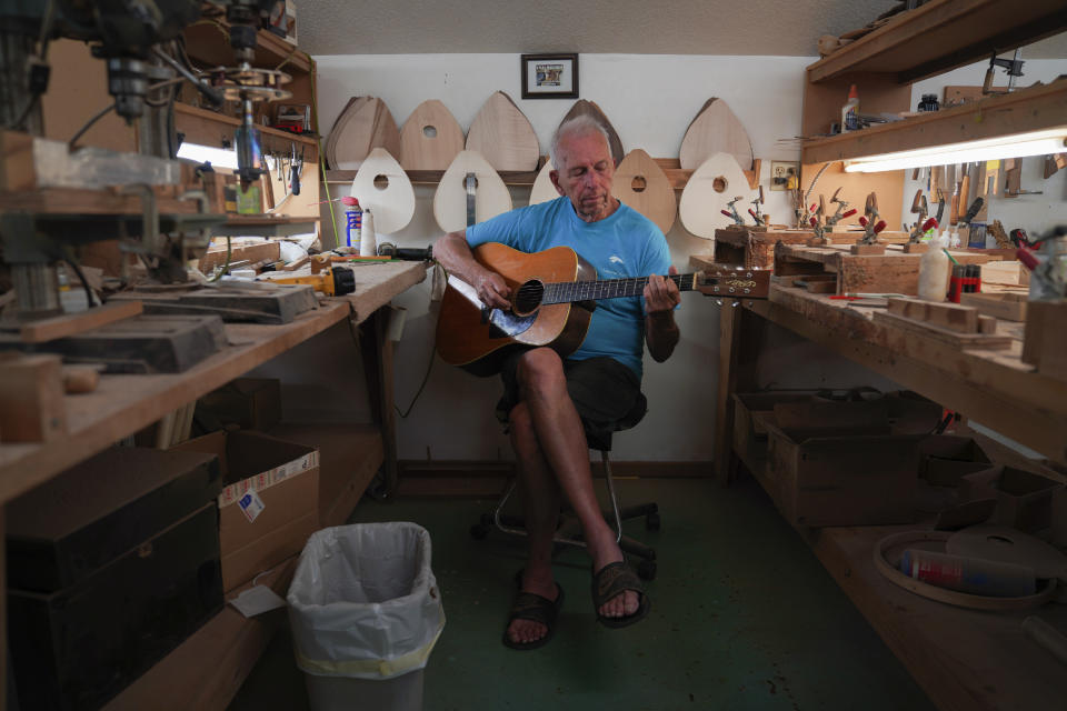 Mike Dulak plays guitar in his mandolin workshop in Rocheport, Mo., Friday, Sept. 8, 2023. Over the past 30 years, Dulak has made thousands of mandolins, and says he finds a sense of spirituality in working with the wood, just as he does playing his guitar. But Dulak, along with the largest grouup of Americans, does not associate himself with any religion. (AP Photo/Jessie Wardarski)
