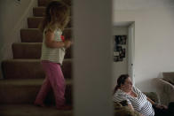 In this Wednesday, Sept. 5, 2018, photo, middle-school English teacher Maryam Powers sits on her sofa as her 2-year-old daughter walks up the steps leading to the master bedroom in Salinas, Calif. Powers rents out the master bedroom for $800 a month to afford the mortgage on the three-bedroom home she purchased in 2015. "I work, work, work, work, work. I take every extra pay job I can do, and I never quite get ahead," Powers said one recent evening after school. (AP Photo/Jae C. Hong)