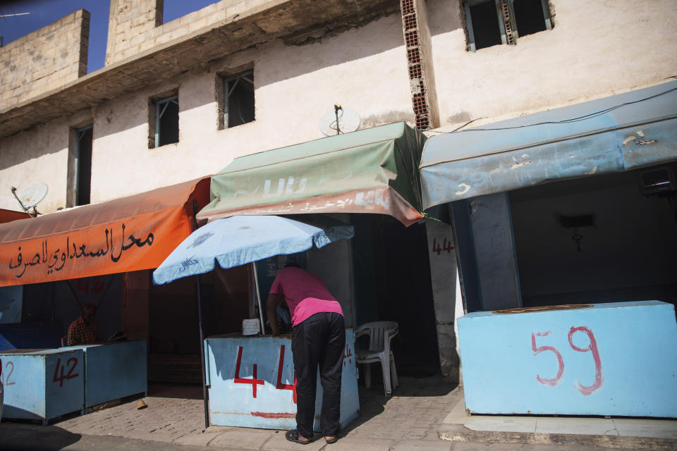 In this Tuesday, Sept. 24, 2019 photo, informal exchange offices line a street on a border town of Ben Garden, southern Tunisia. Tunisia is where the money earned off the suffering of migrants is sent to be whitewashed and to some extent recycled into the militia operations in Libya. In Ben Gardane, dozens of money-changing stalls transform Libyan dinars, dollars and euros into Tunisian currency before the money continues on its way to the capital, Tunis. (AP Photo/Mosa'ab Elshamy)