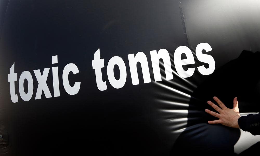 An environmental activist pushes a giant ball with the words, “toxic tonnes” during a protest over carbon pricing reforms outside the European Parliament in Brussels