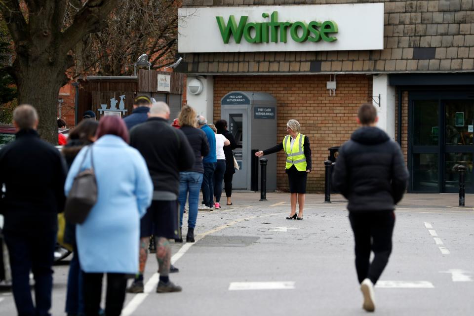 A member of staff enforces social distancing rules in a queue outside a Waitrose supermarket in Frimley, south west of London on March 29, 2020, as life in Britain continues during the nationwide lockdown to combat the novel coronavirus pandemic. - Prime Minister Boris Johnson warned Saturday the coronavirus outbreak will get worse before it gets better, as the number of deaths in Britain rose 260 in one day to over 1,000. The Conservative leader, who himself tested positive for COVID-19 this week, issued the warning in a leaflet being sent to all UK households explaining how their actions can help limit the spread. "We know things will get worse before they get better," Johnson wrote. (Photo by Adrian DENNIS / AFP) (Photo by ADRIAN DENNIS/AFP via Getty Images)