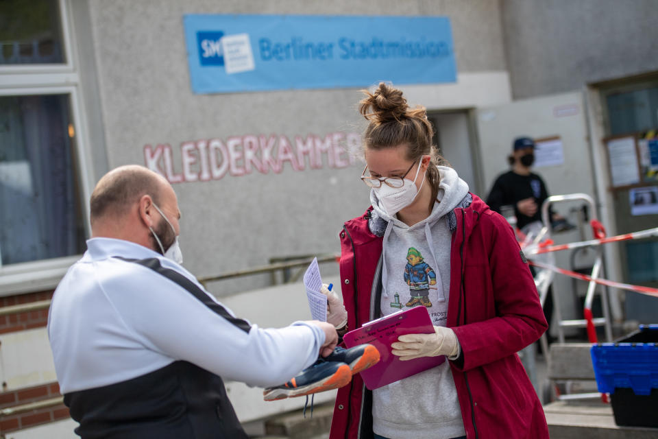 Maja Tussing (r) arbeitet im Rahmen ihres freiwilligen Sozialen Jahres (FSJ) bei der Berliner Stadtmission. Sie gibt einem 34-jährigen Bewohner ein Paar Schuhe (Bild: Christophe Gateau/dpa)