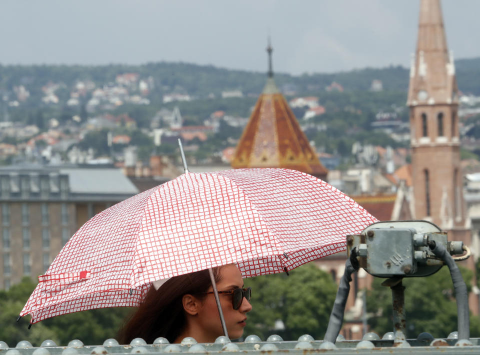 In this photo taken on Wednesday, June 5, 2019, a woman walks across the Chain Bridge over the Danube River in Budapest. A tourism boom in the Hungarian capital has led to major congestion on the river flowing through the city, with sightseeing boats and floating hotels competing for better positions in front of spectacular neo-Gothic buildings, ornate bridges and churches lining the Danube. (AP Photo/Laszlo Balogh)