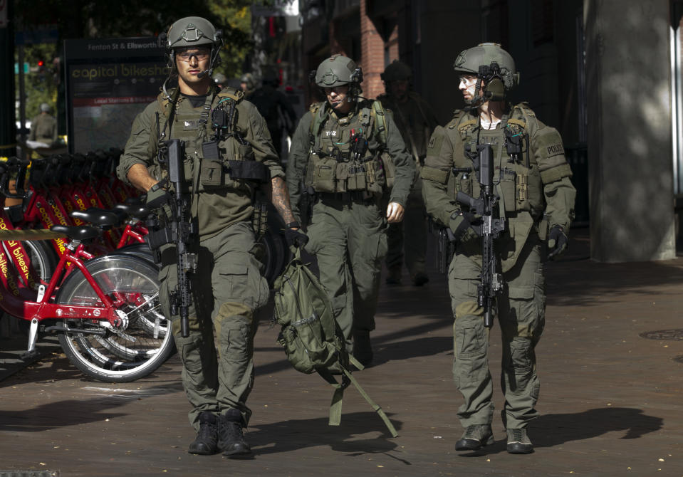 Montgomery police officers in tactical gear exit a parking garage where a police officer was shot, in downtown Silver Spring, Md., Monday, Oct. 14, 2019. Police in Montgomery County, Maryland, said they were searching for at least one person after an officer was found shot in a parking garage in downtown Silver Spring on Monday. (AP Photo/Jose Luis Magana)