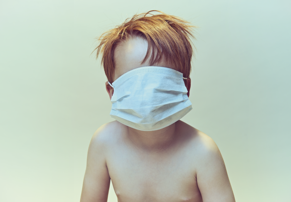 A young child with a mask pulled up over their face.