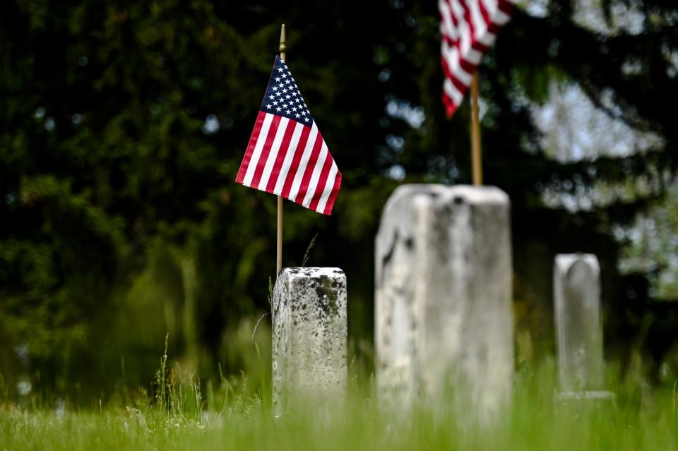 Flags fastened to veteran grave stones on Tuesday, May 23, 2023, at Mt. Hope Cemetery in Lansing.