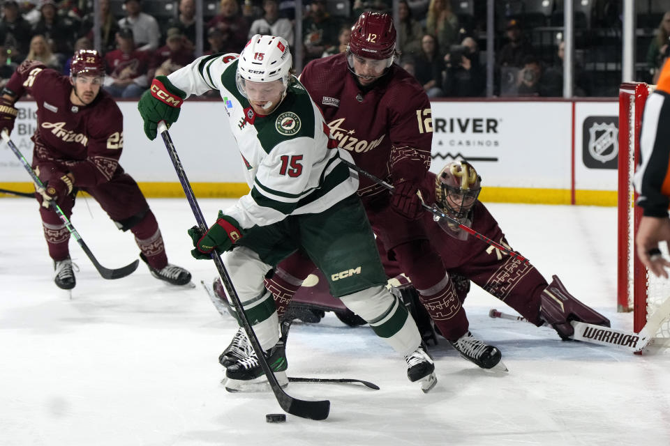 Minnesota Wild center Mason Shaw (15) takes the puck from Arizona Coyotes defenseman Connor Mackey in the first period during an NHL hockey game, Sunday, March 12, 2023, in Tempe, Ariz. (AP Photo/Rick Scuteri)