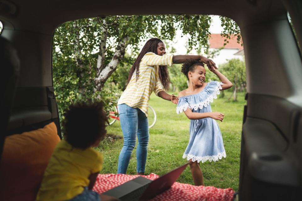 summer activities daughter dancing with mom with younger sibling in the car watching