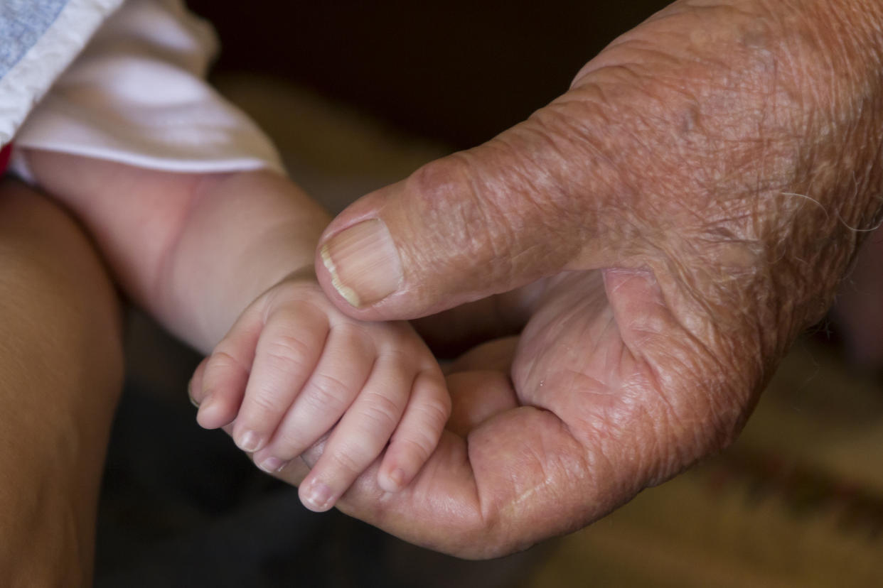 Old man hand holding newborn baby