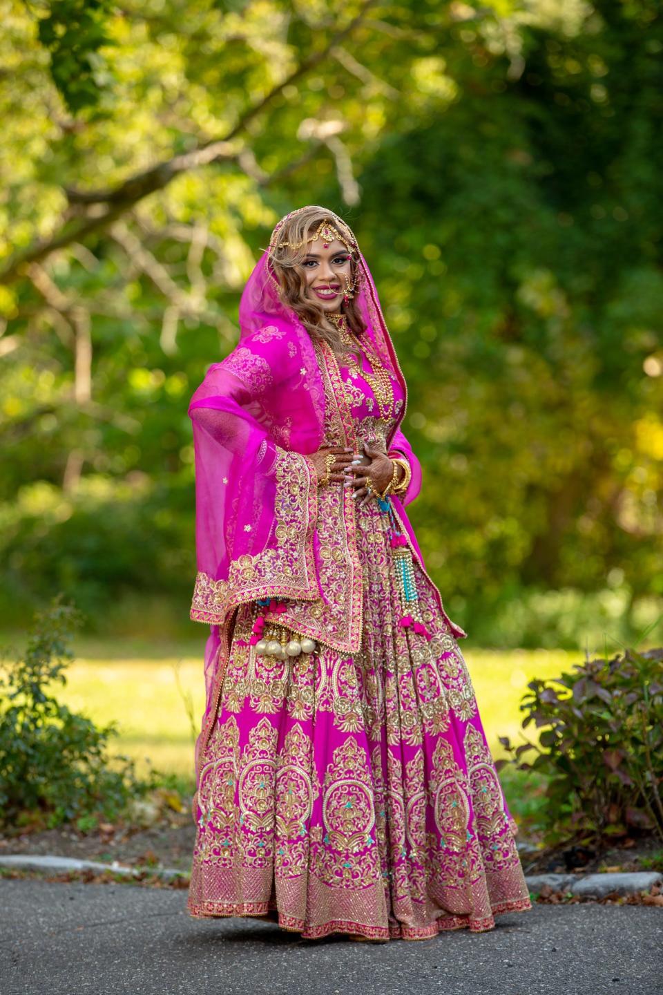 A bride stands in her pink bridal lehenga.