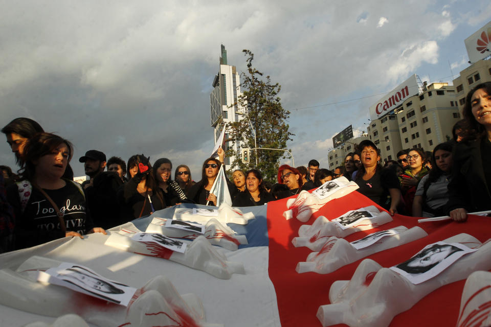 People hold a flag with missing and murdered women's photos during a march in Santiago, Chile on October 19.&nbsp;