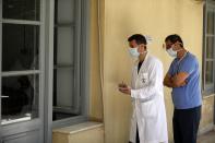 In this photo taken on Friday, May 8, 2020, internal medicine Anastasios Kollias, left, keeps notes as ICU consultant Marios Karvouniaris looks on as their colleagues examining patients inside the COVID-19 Clinic of Sotiria Hospital in Athens. Greece's main hospital for the treatment of COVID-19 is also the focus of a hands-on training program for dozens of medical students who volunteered to relieve hard-pressed doctors from their simpler duties while gaining a close peek at the front lines of a struggle unmatched in modern medical history. (AP Photo/Thanassis Stavrakis)