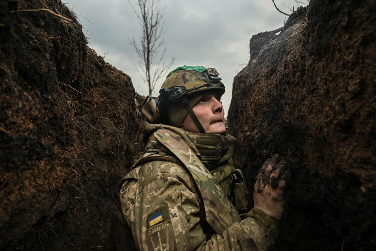 A Ukrainian serviceman takes cover in a trench during shelling next to a 105mm howitzer near the city of Bakhmut (AFP via Getty Images)