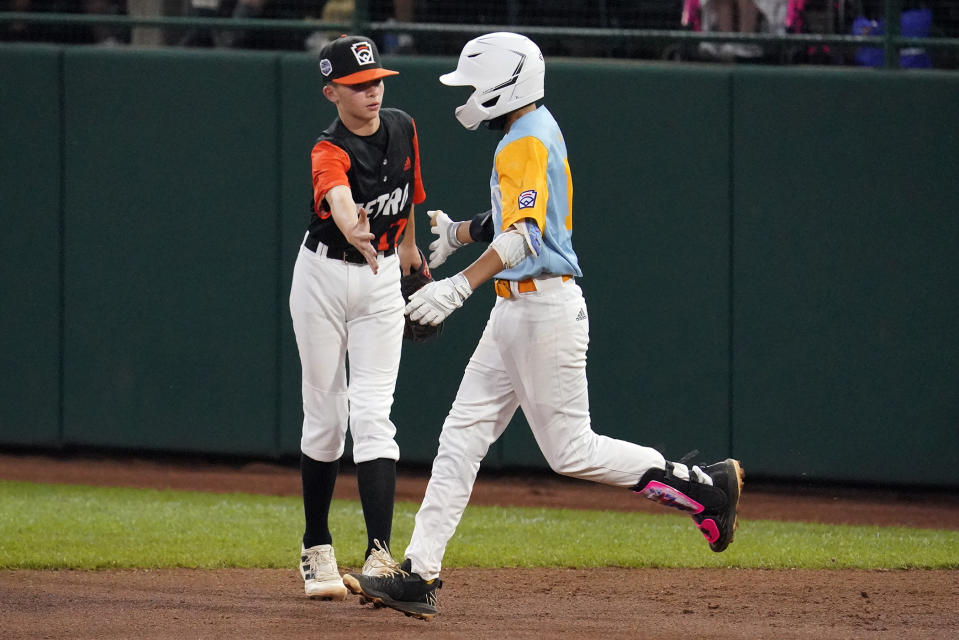 Honolulu's Keko Payanal, right, is congratulated by Massapequa, N.Y.'s Joey Lionetti (17) as he rounds first after hitting a two-run home run during the fourth inning of a baseball game at the Little League World Series in South Williamsport, Pa., Friday, Aug. 19, 2022. (AP Photo/Gene J. Puskar)