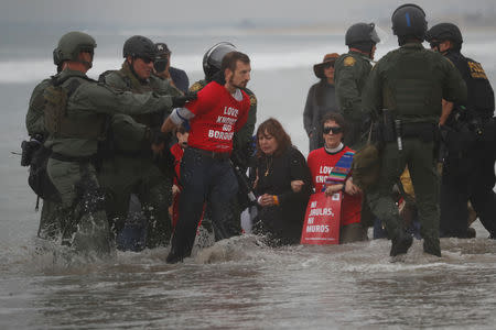 U.S. Customs and Border Protection (CBP) officials detain a man during a gathering in support of the migrant caravan in San Diego, U.S., close to the border wall between the United States and Mexico, as seen from Tijuana, Mexico December 10, 2018. REUTERS/Carlos Garcia Rawlins