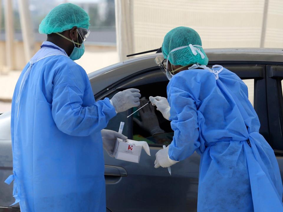 Health workers collect a specimen at a drive-thru testing and screening facility for the coronavirus, in Karachi, Pakistan, Monday, April 6, 2020. Authorities in Pakistan's Sindh province established the first ever drive-thru coronavirus testing facility in Pakistan as part of to control the spread of pandemic coronavirus in the province. (AP Photo/Fareed Khan)