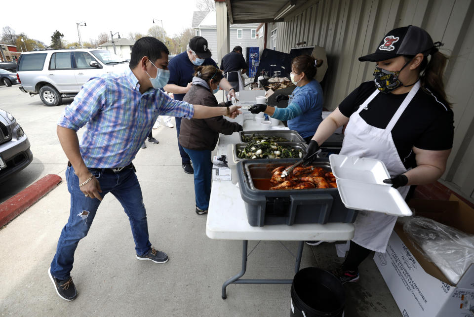 Vanessa Salais, right, of West Liberty, Iowa, serves chicken dinners during a fundraiser for the Omar Martinez family, Saturday, April 25, 2020, in West Liberty, Iowa. Martinez's family had been living the American dream after immigrating from Mexico in the 1990s and settling in this small town in eastern Iowa, but their lives fell apart after coronavirus infections spread from his mother to his sister and his father. (AP Photo/Charlie Neibergall)