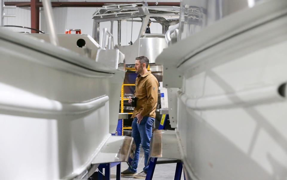 Micah Bowers, CEO of Inventech Marine Solutions, is framed by boats currently under construction while giving a tour of one of their production facilities in the Port of Bremerton on Friday, March 29, 2024.