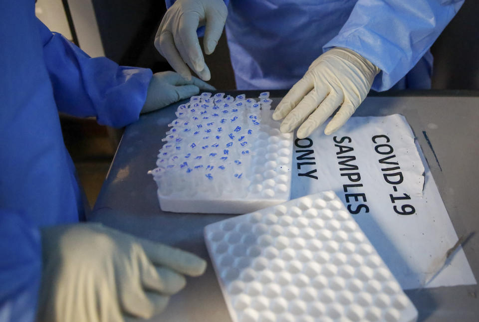 In this photo taken Sunday, April 5, 2020, laboratory technicians handle microcentrifuge tubes containing patient samples to be tested for the new coronavirus that causes COVID-19, at the Pathologists Lancet Kenya laboratory in Nairobi, Kenya. The company, which is offering tests to patients with a doctor's referral, was previously having to send samples to South Africa for testing but is now completing the testing in-house in Kenya. (AP Photo/Brian Inganga)