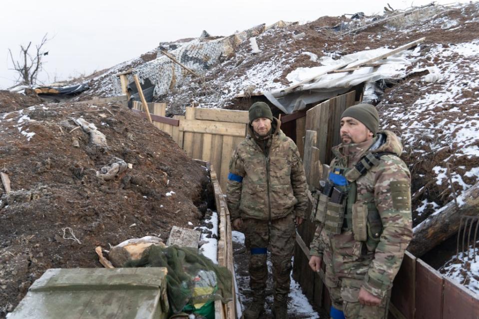 Two Ukrainian soldiers stand in a trench at the zero line south of the Russian-occupied city of Bakhmut. The top of the hill behind them marks the beginning of no man’s land. (Photo via Bennett Murray)