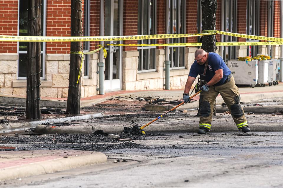 A Kyle firefighter clears Center Street of debris after a fire destroyed two downtown businesses early Thursday.