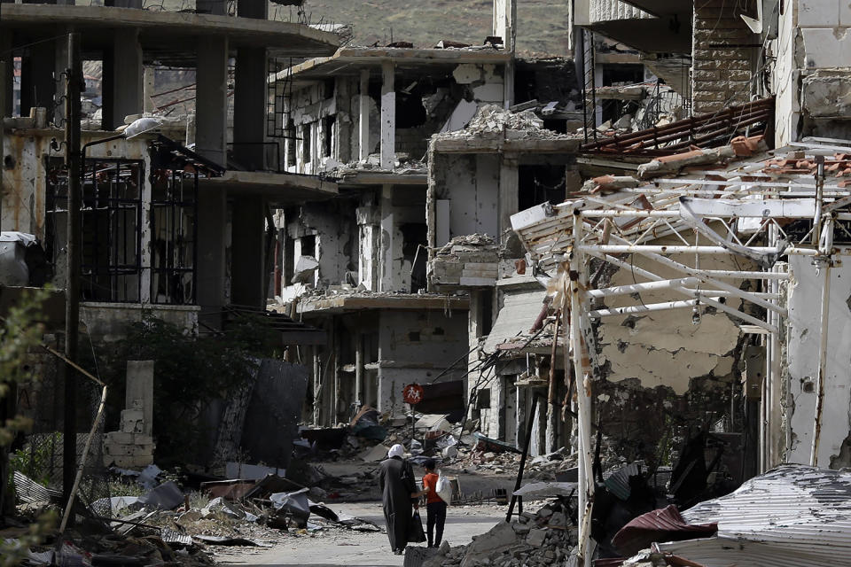 Residents walk through damaged streets in Syria