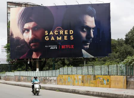 FILE PHOTO: A man rides his scooter past a hoardings of Netflix's new television series "Sacred Games" in Bengaluru, India, July 11, 2018. REUTERS/Abhishek N. Chinnappa