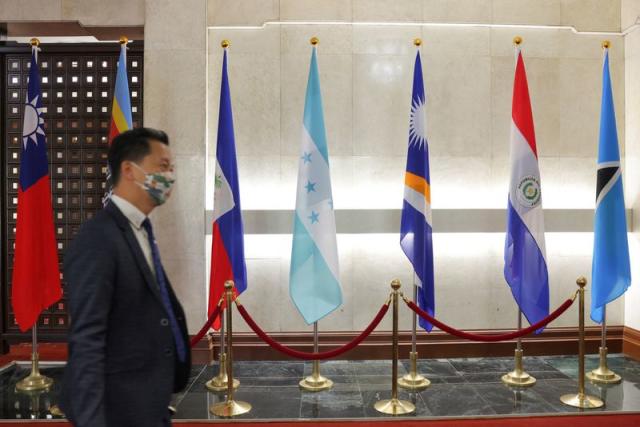 A man walks in front of flags of Honduras, Taiwan, and other countries, displayed at the Ministry of Foreign Affairs building in Taipei