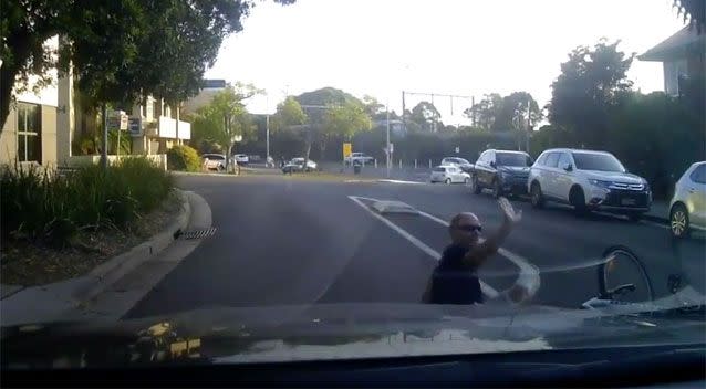 The rider tumbles to the ground before putting his hand up in apology. Source: Facebook/ Dash Cam Owners Australia