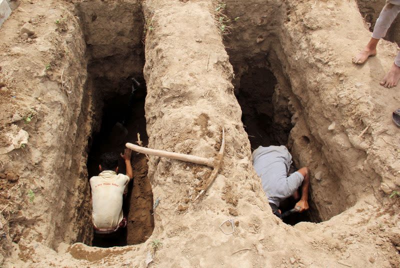 FILE PHOTO: People dig graves at a cemetery where victims of the coronavirus disease (COVID-19) are buried in Taiz