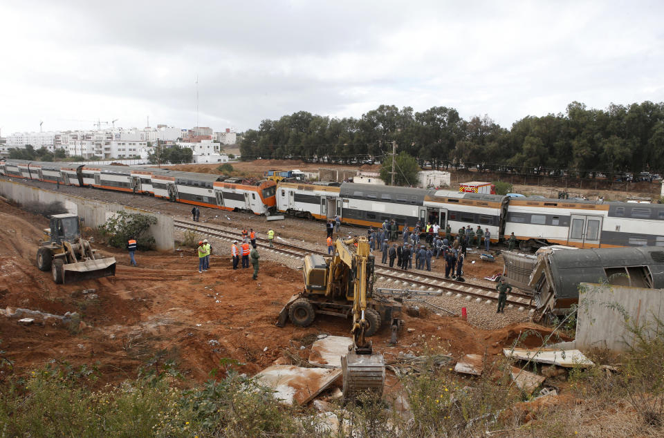 Workers gather by a derailed train Tuesday Oct.16, 2018 near Sidi Bouknadel, Morocco. A shuttle train linking the Moroccan capital Rabat to a town further north on the Atlantic coast derailed Tuesday, killing several people and injuring dozens, Moroccan authorities and the state news agency said. (AP Photo/Abdeljalil Bounhar)